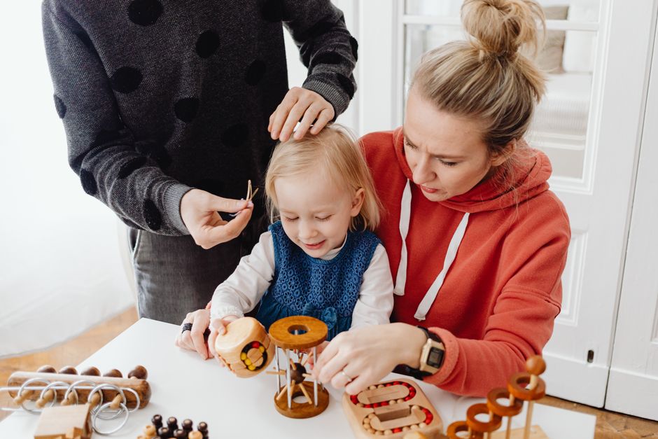 A family spending quality time playing with wooden educational toys indoors.